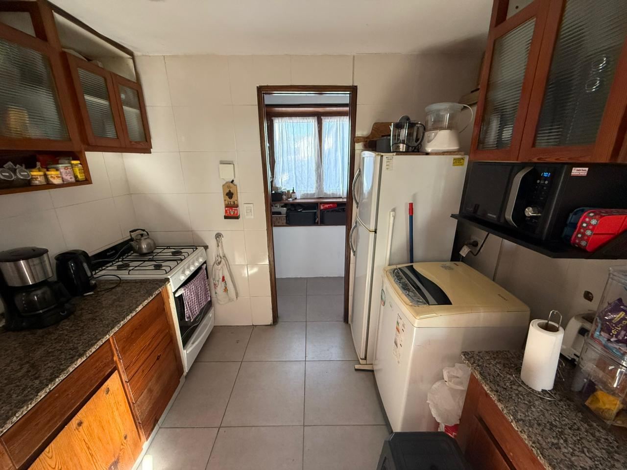 Cocina separada con muebles bajo mesada de madera, alacenas y ventana al exterior