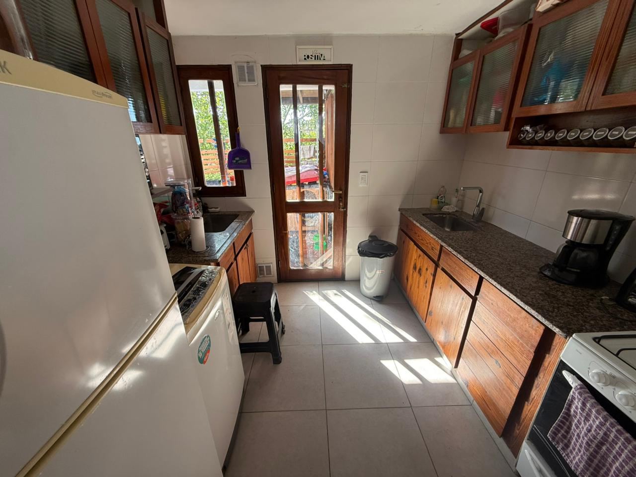 Cocina desde el otro extremo, con heladera, horno y salida al balcón